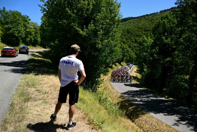 A bystander wearing a t-shirt reading "France" watches as the pack of riders (peloton) rides in the first ascent of the 7th (out of 9) stage of the fifth edition of the Women's Tour de France cycling race, 146.8 km from Voulte-sur-Rhone to The Mont Ventoux, at The Mont Ventoux, southeastern France on August 7, 2026. (Photo by NICOLAS TUCAT / AFP)