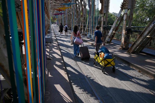 First visitors cross a decorated bridge to arrive at the site of the annual Sziget Festival at Obuda Island, in Budapest, on August 7, 2026. The 33rd Sziget Festival will take place from August 11 to 15, 2026. (Photo by Attila KISBENEDEK / AFP)