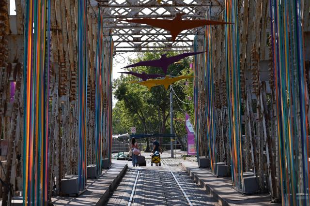 First visitors cross a decorated bridge to arrive at the site of the annual Sziget Festival at Obuda Island, in Budapest, on August 7, 2026. The 33rd Sziget Festival will take place from August 11 to 15, 2026. (Photo by Attila KISBENEDEK / AFP)