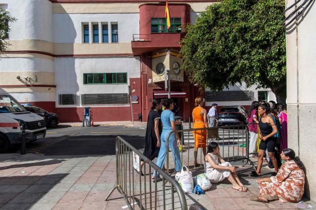 Migrant minors wait outside the National Police headquarters to begin identification and registration procedures in the Spanish North African enclave of Ceuta on August 7, 2026, following a mass influx of migrants from Morocco in recent days. Of the 72,000 migrants who reached Ceuta, 70,000 have returned to Morocco, according to official Spanish figures, which have recorded 80 deaths. Morocco's interior ministry has said 11 people died on the Moroccan side of the border, all but one by drowning. Those who remain in Ceuta -- including hundreds of unaccompanied children -- face dire living conditions with little access to food, water, shelter and sanitation. (Photo by Eitan ABRAMOVICH and Antonio Sempere / AFP)