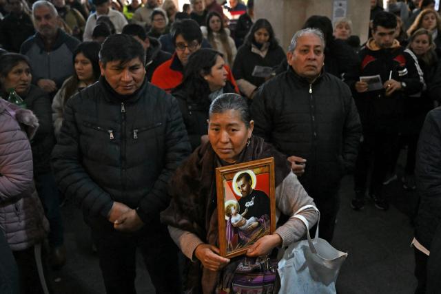 A woman holds an image of Saint Cajetan, patron saint of work and bread, as faithful pray at the San Cayetano Church in Buenos Aires on August 7, 2026. Every year on the feast of Saint Cajetan, thousands of Catholics visit the shrine to pay homage to the saint and pray for employment and prosperity. (Photo by Luis ROBAYO / AFP)