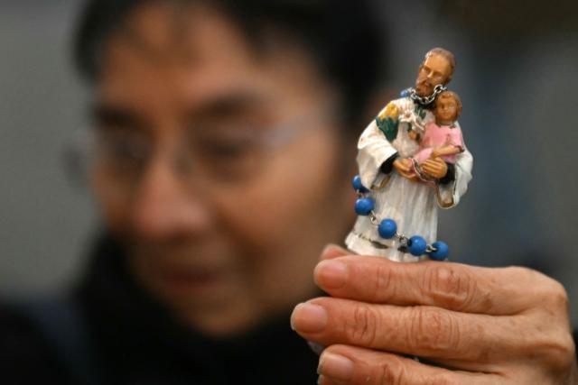 A woman holds a statuette of Saint Cajetan, patron saint of work and bread, as faithful pray at the Saint Cajetan Church in Buenos Aires on August 7, 2026. Every year on the feast of Saint Cajetan, thousands of Catholics visit the shrine to pay homage to the saint and pray for employment and prosperity. (Photo by Luis ROBAYO / AFP)