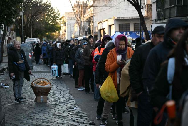 The faithful stand in line waiting to enter the church of Saint Cajetan, patron saint of work and bread, in Buenos Aires on August 7, 2026. Every year on the feast of Saint Cajetan, thousands of Catholics visit the shrine to pay homage to the saint and pray for employment and prosperity. (Photo by Luis ROBAYO / AFP)