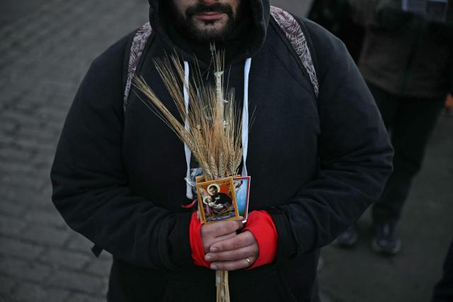 A man holds an image of Saint Cajetan, patron saint of work and bread, as faithful pray at the Saint Cajetan Church in Buenos Aires on August 7, 2026. Every year on the feast of Saint Cajetan, thousands of Catholics visit the shrine to pay homage to the saint and pray for employment and prosperity. (Photo by Luis ROBAYO / AFP)