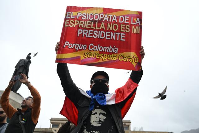 A demonstrator holds a banner reading "The psychopath De la Espriella is not my president because Colombia deserves respect" during a protest by supporters of outgoing Colombian President Gustavo Petro at Bolivar Square in Bogota on August 7, 2026, ahead of the inauguration of Colombian President-elect Abelardo de la Espriella. (Photo by Raul ARBOLEDA / AFP)