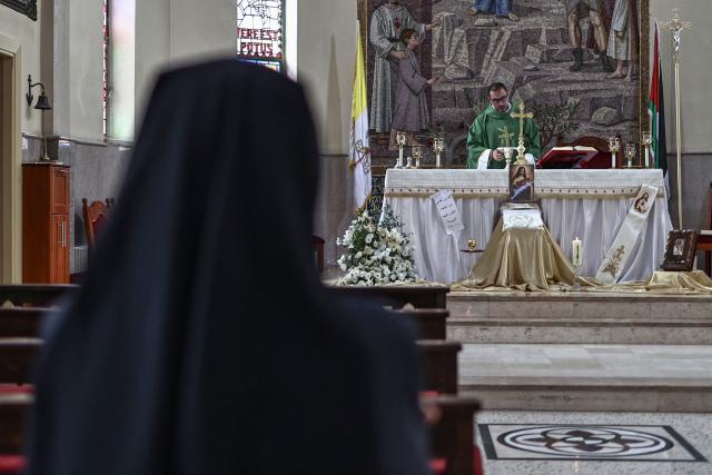 This picture taken on June 22, 2026 shows Father Bashar Fawadleh, a Palestinian Catholic priest of the Latin Patriarchate of Jerusalem who serves as the parish priest of the Christ the Redeemer Church (the Latin Church), leading the service in the Palestinian Christian town of Taybeh, northeast of the city of Ramallah in the Israeli-occupied West Bank. Christians of the West Bank are concentrated in Israeli-annexed east Jerusalem and Bethlehem, as well as Ramallah and several surrounding villages and towns. In the town of Taybeh, east of Ramallah -- the last entirely Christian town in the West Bank -- churches have documented the emigration of more than 15 families since 2023. Its population, now 1,200, stood at 3,000 in the 1980s. (Photo by Zain JAAFAR / AFP) / To go with 'PALESTINIAN-ISRAEL-CONFLICT-CHRISTIANITY, FOCUS by Imad FREIJ