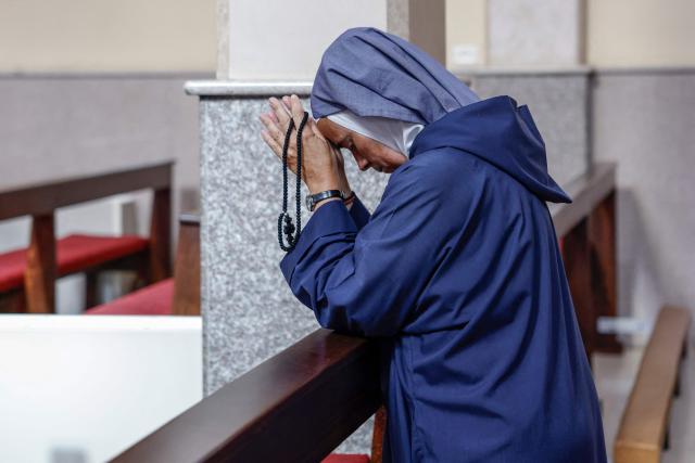 This picture taken on June 22, 2026 shows a Catholic nun praying during a mass at the Latin Monastery (Deir al-Latin) in the Palestinian Christian town of Taybeh, northeast of the city of Ramallah in the Israeli-occupied West Bank. Christians of the West Bank are concentrated in Israeli-annexed east Jerusalem and Bethlehem, as well as Ramallah and several surrounding villages and towns. In the town of Taybeh, east of Ramallah -- the last entirely Christian town in the West Bank -- churches have documented the emigration of more than 15 families since 2023. Its population, now 1,200, stood at 3,000 in the 1980s. (Photo by Zain JAAFAR / AFP) / To go with 'PALESTINIAN-ISRAEL-CONFLICT-CHRISTIANITY, FOCUS by Imad FREIJ