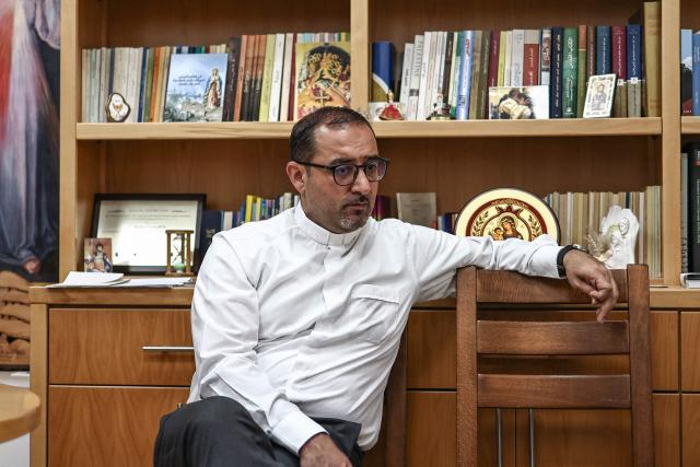 This picture taken on June 21, 2026 shows Father Bashar Fawadleh, a Palestinian Catholic priest of the Latin Patriarchate of Jerusalem who serves as the parish priest of the Christ the Redeemer Church (the Latin Church) poses for a photo during an interview with AFP in the Palestinian Christian town of Taybeh, northeast of the city of Ramallah in the Israeli-occupied West Bank. Christians of the West Bank are concentrated in Israeli-annexed east Jerusalem and Bethlehem, as well as Ramallah and several surrounding villages and towns. In the town of Taybeh, east of Ramallah -- the last entirely Christian town in the West Bank -- churches have documented the emigration of more than 15 families since 2023. Its population, now 1,200, stood at 3,000 in the 1980s. (Photo by Zain JAAFAR / AFP) / To go with 'PALESTINIAN-ISRAEL-CONFLICT-CHRISTIANITY, FOCUS by Imad FREIJ