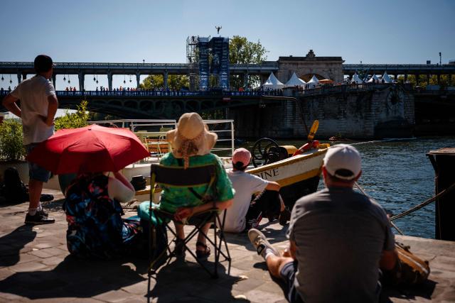 Spectators watch an athlete compete in the men’s 20m high diving event during the LEN European Aquatics Championships, alongside the Seine River, in Paris on August 7, 2026. (Photo by Dimitar DILKOFF / AFP)