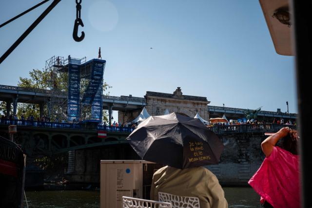 An elderly couple watches an athlete compete in the men’s 20m high diving event during the LEN European Aquatics Championships, alongside the Seine River, in Paris on August 7, 2026. (Photo by Dimitar DILKOFF / AFP)
