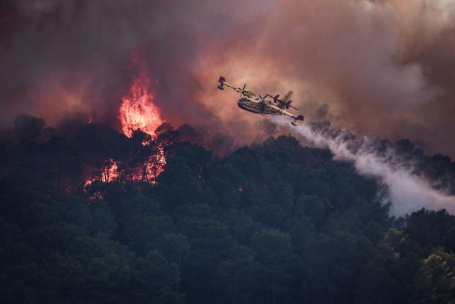 (FILES) A French Civil Security Canadair CL-415 aircraft sprays water on a forest surrounding Cotignac, southeastern France on July 23, 2026 during a wildfire. The fire that broke out at the end of July in the Gros Bessillon massif, in the central Var, is now "contained" after 18 days of firefighting operations, the prefecture of this department in southeastern France announced on August 7, 2026, describing it as "unprecedented in terms of its duration. (Photo by Thibaud MORITZ / AFP)