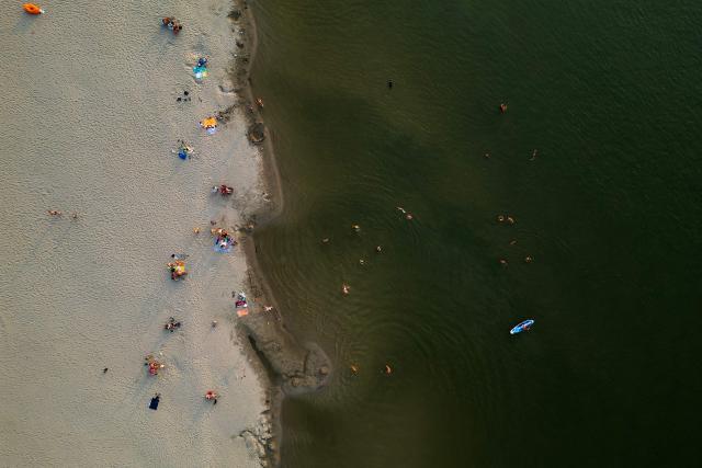 This aerial photo shows people swiming in the low waters of the Danube River near Novi Sad, Serbia, on August 7, 2026, as prolonged hot and dry weather continues to lower water levels across the country. Scientists say global warming is increasing droughts and causing weather emergencies to become more extreme and more frequent. Prolonged drought and hot weather across Europe have pushed water levels along the Danube river to record seasonal lows, reaching its lowest flow rate in the last 30 years. (Photo by Andrej ISAKOVIC / AFP)