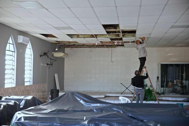 Members of the Evangelical Church Assembleia de Deus Madureira fix on August 7, 2026, the ceiling destroyed by heavy winds during a church service on August 6, in Sao Leopoldo, Rio Grande do Sul state, Brazil. (Photo by PEDRO H. TESCH / AFP)
