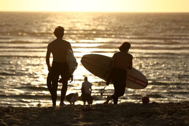 Surfers walk towards the ocean at Le Porge beach, Gironde, south-western France, on August 7, 2026. (Photo by ROMAIN PERROCHEAU / AFP)