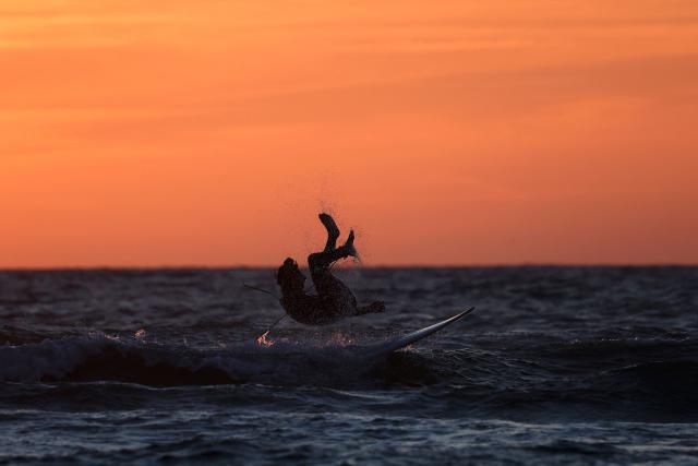 A surfer falls into the water off Le Porge beach, Gironde, south-western France, on August 7, 2026. (Photo by ROMAIN PERROCHEAU / AFP)