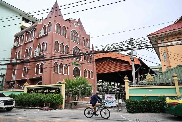 People drive past Debsirin Nonthaburi secondary school the day after a 14-year old student shot dead 5 school staff, after also killing his grandparents at home, in Nonthaburi on August 8, 2026. (Photo by Lillian SUWANRUMPHA / AFP)