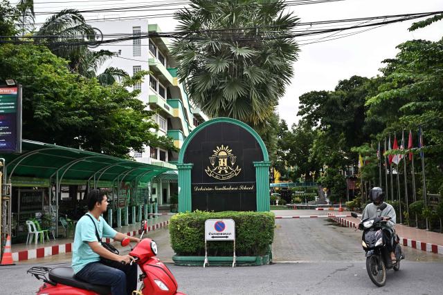 People drive past Debsirin Nonthaburi secondary school the day after a 14-year old student shot dead 5 school staff, after also killing his grandparents at home, in Nonthaburi on August 8, 2026. (Photo by Lillian SUWANRUMPHA / AFP)