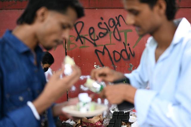 (FILES) Cockroach Janta Party (CJP) supporters eat near a wall mural at Jantar Mantar in New Delhi on July 22, 2026 during the ongoing protest to demand the resignation of India's Education Minister Dharmendra Pradhan over alleged NEET exam irregularities. Two weeks after youth-led protests forced India's education minister to resign, Prime Minister Narendra Modi's government is grappling with the fallout from one of its toughest political challenges in years. Led by the online Cockroach Janta Party (CJP), the demonstrations spread from New Delhi to other cities, broadening from anger over exam irregularities into a wider movement over unemployment, opportunities for young people and what critics describe as Modi's increasingly authoritarian rule. (Photo by Sajjad HUSSAIN / AFP)