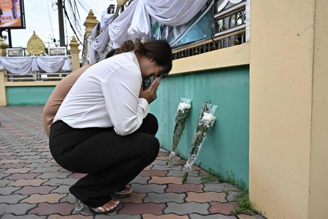 People leave flowers outside Debsirin Nonthaburi secondary school the day after a 14-year old student shot dead 5 school staff, after also killing his grandparents at home, in Nonthaburi on August 8, 2026. (Photo by Lillian SUWANRUMPHA / AFP)