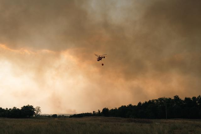 A Kamov Ka-32 firefighting helicopter flies amid the smoke during a wildfire in Deliblatska Pescara (Deliblato Sands), near the village of Sumarak, some 70 kilometres northeast of Belgrade, on August 7, 2026. Firefighters were battling wildfires across the Balkans as days of high temperatures and drought conditions continue to drive blazes in several countries, including Serbia. (Photo by Uros Arsic / AFP)