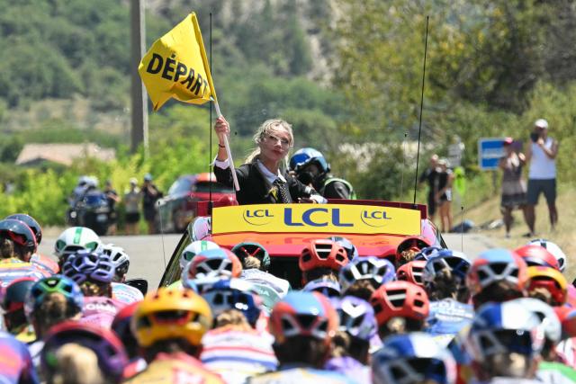TOPSHOT - Director of the race Marion Rousse (C) waves a flag announcing the start of the stage 8 of the Women's Tour de France cycling race, 171.9 km from Sisteron to Nice, in Sisteron, southeastern France on August 8, 2026. (Photo by NICOLAS TUCAT / AFP)