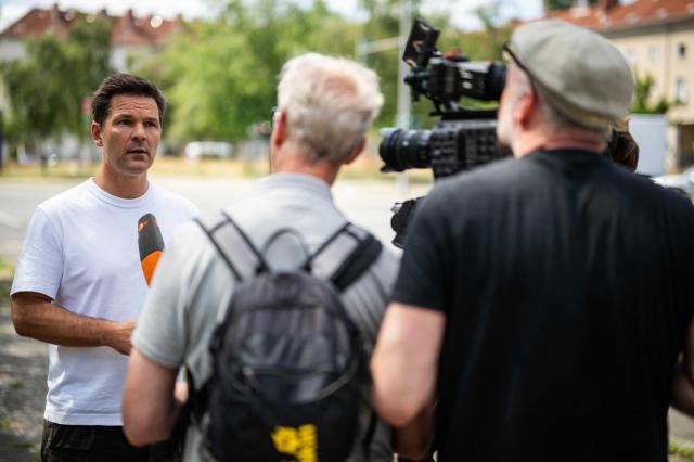 Steffen Krach (L), the Social Democratic Party's (SPD) main candidate in upcoming regional elections in Berlin, speaks to reporters during a campaign stop in Berlin's Wedding district on August 8, 2026. Berlin goes to the polls on September 20, 2026. (Photo by John MACDOUGALL / AFP)