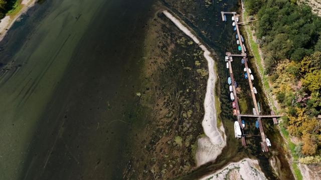 This aerial view shows boats laying on the dried Ticino river, in Linarolo, near Pavia, northern Italy, on August 8, 2026. (Photo by Stefano RELLANDINI / AFP)