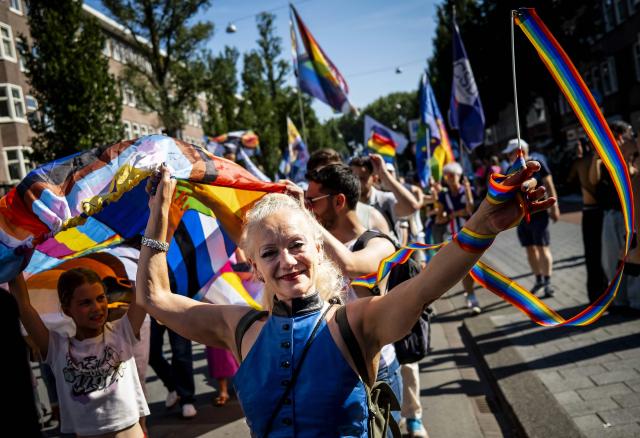 Participants hold rainbow flags as they walk towards Museumplein during the Pride March in Amsterdam, on August 8, 2026. The gathering marks the conclusion of WorldPride, which took place in Amsterdam this year. (Photo by Sem van der Wal / ANP / AFP) / Netherlands OUT