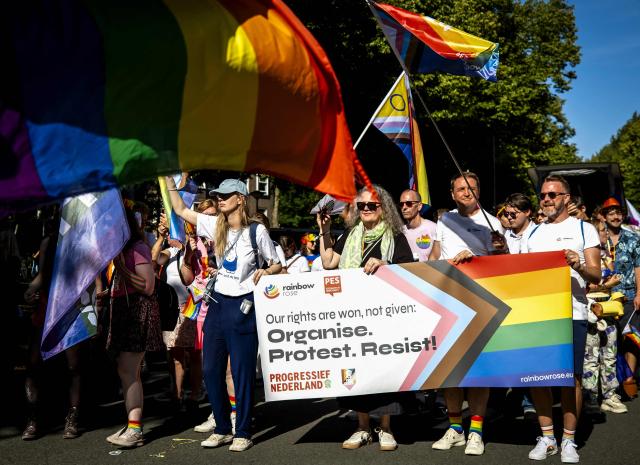 Participants hold a banner and rainbow flags as they walk towards Museumplein during the Pride March in Amsterdam, on August 8, 2026. The gathering marks the conclusion of WorldPride, which took place in Amsterdam this year. (Photo by Sem van der Wal / ANP / AFP) / Netherlands OUT