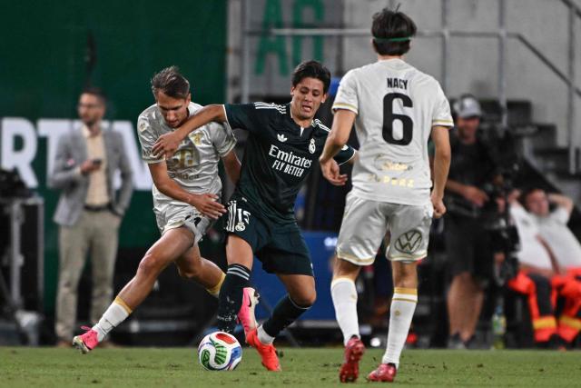 Real Madrid's Turkish midfielder #15 Arda Guler (C) and Ferencvaros' Hungarian forward #74 Szilard Szabo (L) vie for the ball during the pre-season football match between Ferencvaros and Real Madrid in Budapest, Hungary on August 8, 2026. Real Madrid on August 6, 2026 announced a new six-year deal for star forward Vinicius Junior and the signing of teenage sensation Yan Diomande in a major boost to their quest to end a two-year trophy drought. (Photo by Attila KISBENEDEK / AFP)