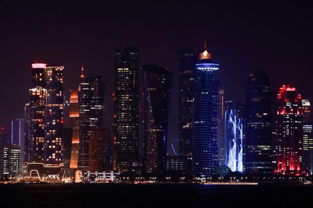 The skyline of illuminated high-rise buildings is seen along the Corniche Promenade in Doha on August 8, 2026. (Photo by KARIM JAAFAR / AFP)