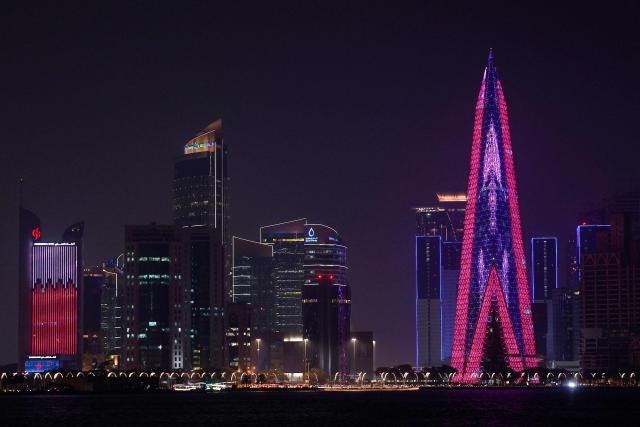 The skyline of illuminated high-rise buildings is seen along the Corniche Promenade in Doha on August 8, 2026. (Photo by KARIM JAAFAR / AFP)