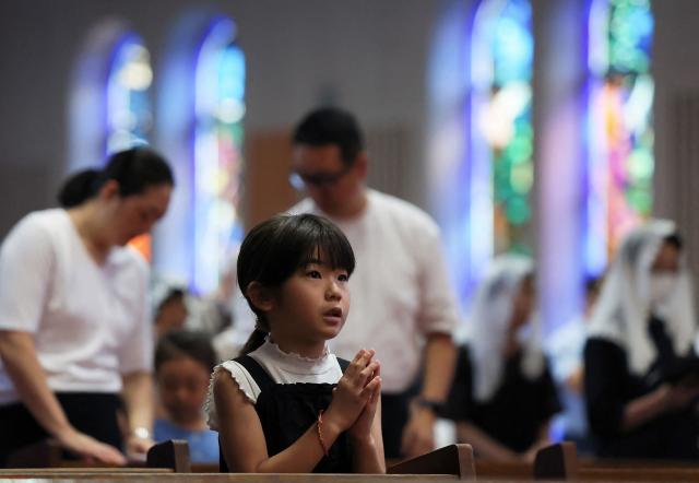 People pray at a mass held at Urakami Cathedral on August 9, 2026 in Nagasaki, marking the 81st anniversary of the atomic bombing. (Photo by JIJI Press / AFP) / Japan OUT