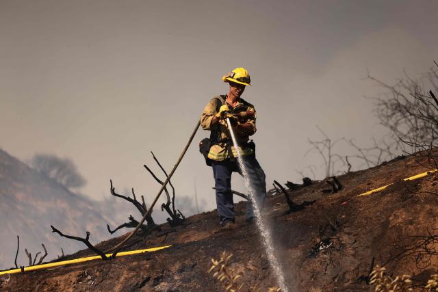 A Los Angeles firefighter battles the Walnut Fire in the Wildwood Canyon shortly after breaking out on August 8, 2026 in Burbank, California. The blaze that started on Saturday afternoon forced evacuation orders and warnings to nearby residents. (Photo by David Swanson / AFP)