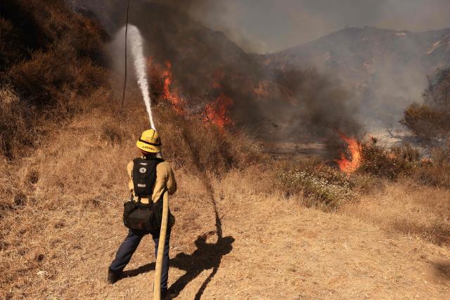A Los Angeles firefighter battles the Walnut Fire in the Wildwood Canyon shortly after breaking out on August 8, 2026 in Burbank, California. The blaze that started on Saturday afternoon forced evacuation orders and warnings to nearby residents. (Photo by David Swanson / AFP)