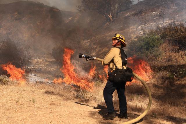 A Los Angeles firefighter battles the Walnut Fire in the Wildwood Canyon shortly after breaking out on August 8, 2026 in Burbank, California. The blaze that started on Saturday afternoon forced evacuation orders and warnings to nearby residents. (Photo by David Swanson / AFP)