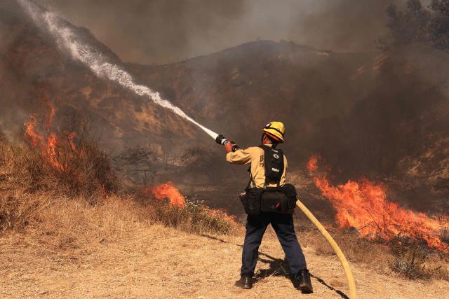 A Los Angeles firefighter battles the Walnut Fire in the Wildwood Canyon shortly after breaking out on August 8, 2026 in Burbank, California. The blaze that started on Saturday afternoon forced evacuation orders and warnings to nearby residents. (Photo by David Swanson / AFP)