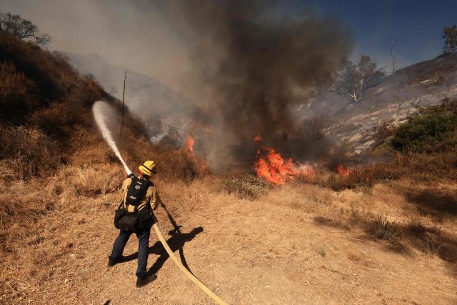 A Los Angeles firefighter battles the Walnut Fire in the Wildwood Canyon shortly after breaking out on August 8, 2026 in Burbank, California. The blaze that started on Saturday afternoon forced evacuation orders and warnings to nearby residents. (Photo by David Swanson / AFP)