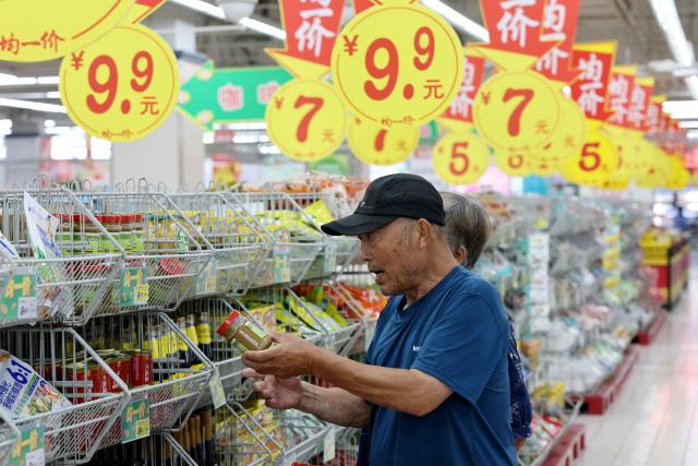 A consumer selects a product at a supermarket in Zaozhuang, in eastern China's Shandong province, on August 9, 2026. (Photo by CN-STR / AFP) / China OUT