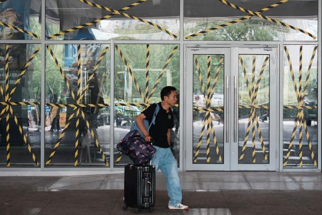 A passenger walks past glass windows taped at a temporary waiting room at Hangzhou railway station in eastern China's Zhejiang province on August 9, 2026, as a precaution against Typhoon Dolphin. (Photo by CN-STR / AFP) / China OUT
