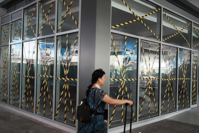 A passenger walks past glass windows taped at a temporary waiting room at Hangzhou railway station in eastern China's Zhejiang province on August 9, 2026, as a precaution against Typhoon Dolphin. (Photo by CN-STR / AFP) / China OUT