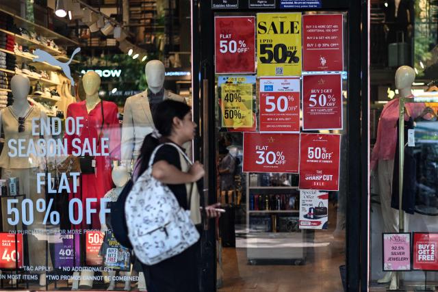 A pedestrian walks past a shop displaying sale advertisements in New Delhi on August 9, 2026. (Photo by Sajjad HUSSAIN / AFP)