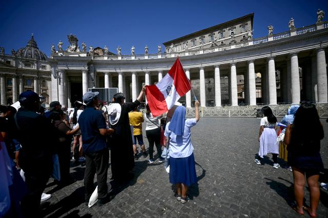 A nun waves a Peruvian national flag as she stands with fellow worshippers during Pope Leo XIV Angelus prayer on St. Peter's Square at The Vatican on August 9, 2026. (Photo by Filippo MONTEFORTE / AFP)
