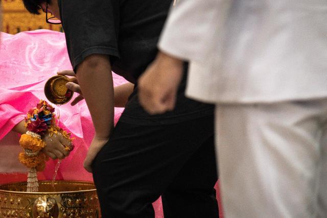 Mourners pour water over the hand of 12-year-old school shooting victim Naphat Chaima during her funeral at the Wat Lat Pla Duk Buddhist temple in Nonthaburi province, north of Thailand's capital Bangkok, on August 9, 2026. A teenage assailant shot his grandparents, using his grandfather's handgun, at their home north of Bangkok on August 7 before going on a killing spree at his secondary school and ultimately turning the gun on himself, according to authorities. (Photo by Chanakarn LAOSARAKHAM / AFP)