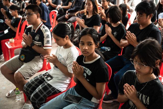 Mourners pray for 12-year-old school shooting victim Naphat Chaima during her funeral at the Wat Lat Pla Duk Buddhist temple in Nonthaburi province, north of Thailand's capital Bangkok, on August 9, 2026. A teenage assailant shot his grandparents, using his grandfather's handgun, at their home north of Bangkok on August 7 before going on a killing spree at his secondary school and ultimately turning the gun on himself, according to authorities. (Photo by Chanakarn LAOSARAKHAM / AFP)