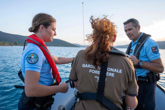 French gendarmes patrol on a boat to monitor for illegal wild camping and forest fire risks around Lake Sainte-Croix, southeastern France on August 8, 2026. At nightfall, two gendarmes scan the shores of Lake Sainte-Croix—located at the gateway to the Verdon Gorge—with binoculars, looking for potential campers. Their mission: to prevent any illegal camping that could spark a fire in the surrounding woodlands. (Photo by Miguel MEDINA / AFP)