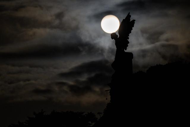 The Sun sets behind the modernist-style sculpture known as "The Exterminating Angel" in the cemetery of Comillas in the province of Cantabria, northern Spain, on August 9, 2026. Spain, one of the few places in the world where the solar eclipse of August 12 will be seen in totality, is beginning preparations for a phenomenon expected to shift traditional summer tourism from beaches to the countryside. (Photo by CESAR MANSO / AFP)