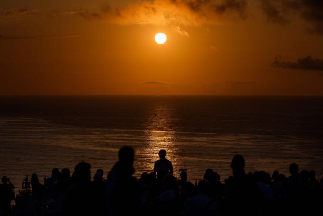 People gather to watch the sunset at "El Rayo Verde" viewpoint, in San Vicente de la Barquera in the province of Cantabria, northern Spain, on August 9, 2026. Spain, one of the few places in the world where the solar eclipse of August 12 will be seen in totality, is beginning preparations for a phenomenon expected to shift traditional summer tourism from beaches to the countryside. (Photo by CESAR MANSO / AFP)