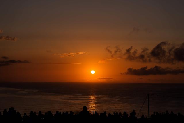People gather to watch the sunset at "El Rayo Verde" viewpoint, in San Vicente de la Barquera in the province of Cantabria, northern Spain, on August 9, 2026. Spain, one of the few places in the world where the solar eclipse of August 12 will be seen in totality, is beginning preparations for a phenomenon expected to shift traditional summer tourism from beaches to the countryside. (Photo by CESAR MANSO / AFP)