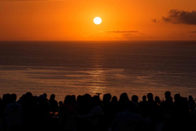 People gather to watch the sunset at "El Rayo Verde" viewpoint, in San Vicente de la Barquera in the province of Cantabria, northern Spain, on August 9, 2026. Spain, one of the few places in the world where the solar eclipse of August 12 will be seen in totality, is beginning preparations for a phenomenon expected to shift traditional summer tourism from beaches to the countryside. (Photo by CESAR MANSO / AFP)